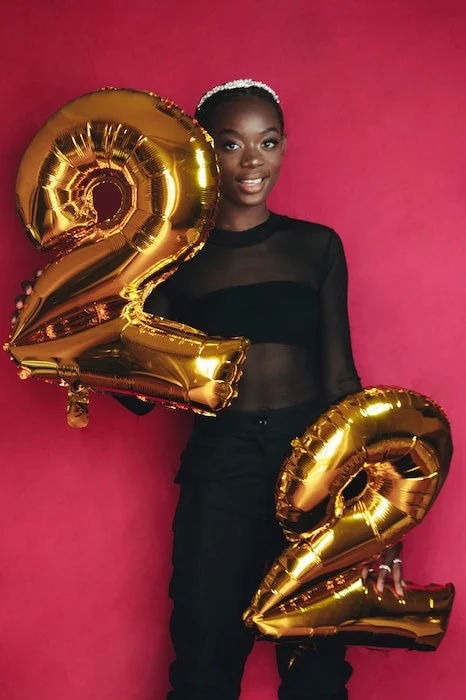 Portrait of young girl holding two two-shaped balloons. 