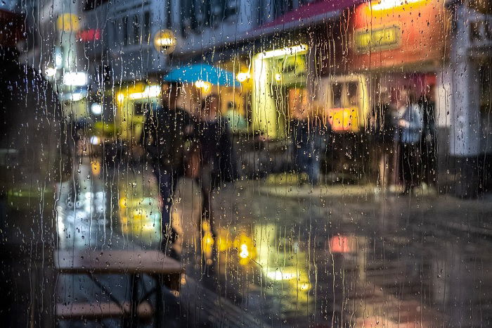 Rain-stained window with a lamp-lit street on the other side