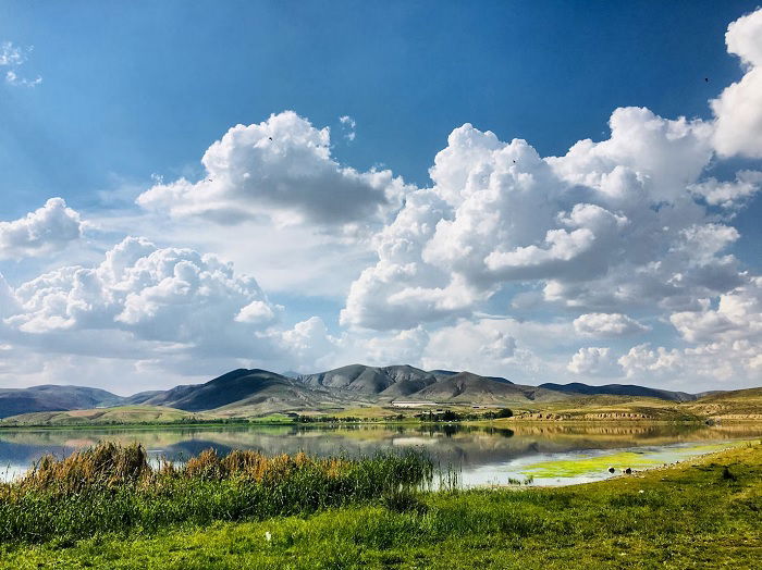 Landscape with lake, mountains, and clouds overhead