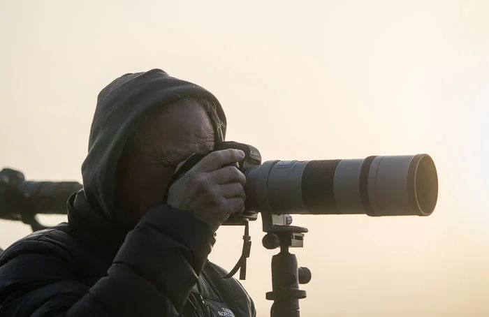 Wildlife photographer using camera with telephoto lens on a tripod