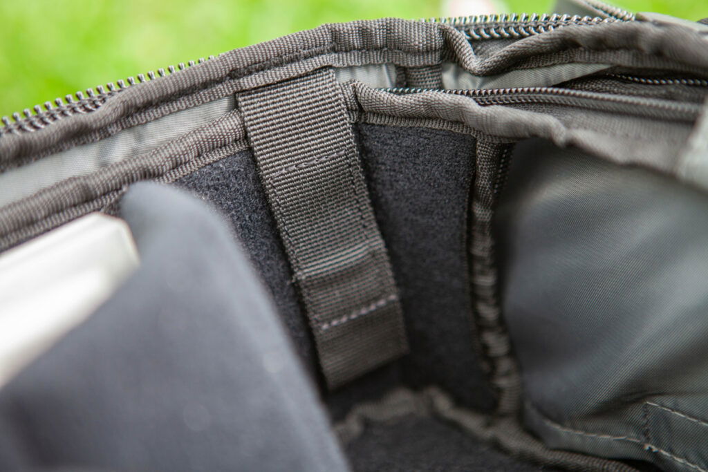 A black carrying case with a gray strap, placed on the grass. 