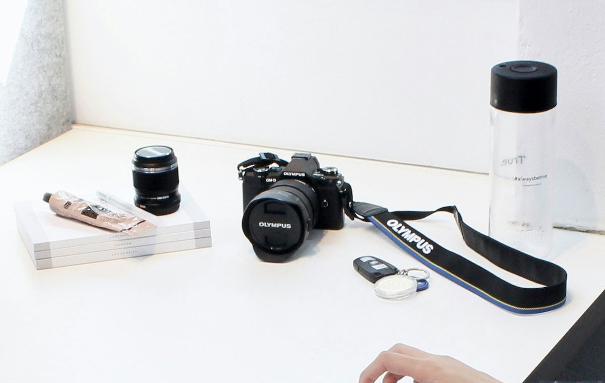 Camera bag, camera lens, camera strap and water bottle on a table. 