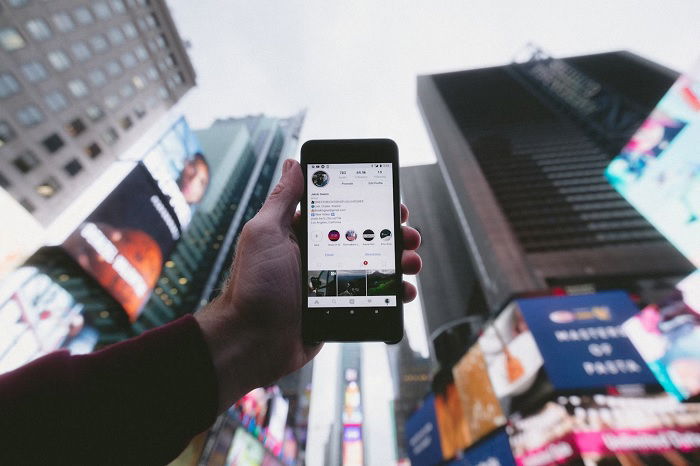 Hand holding a smartphone with Instagram on it in a city