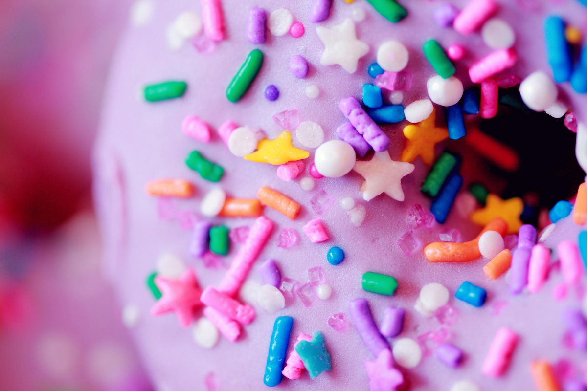 A close-up of a pink donut with frosting and sprinkles.