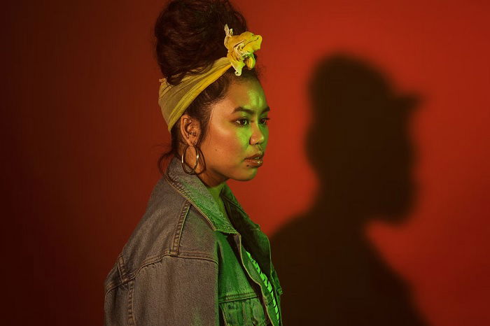 Studio portrait of a young woman with yellow and green lighting