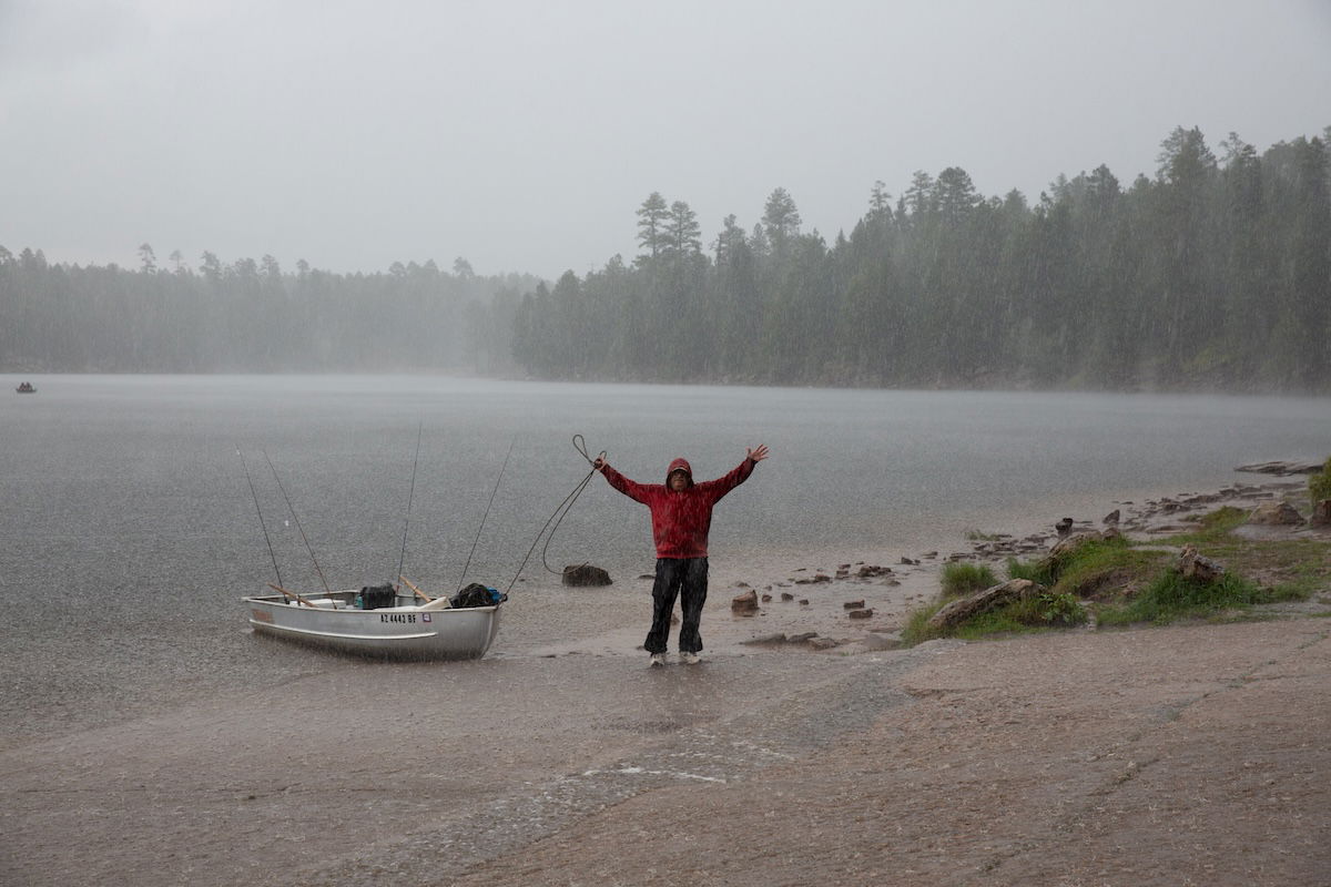 man standing next to a fishing boat in the rain