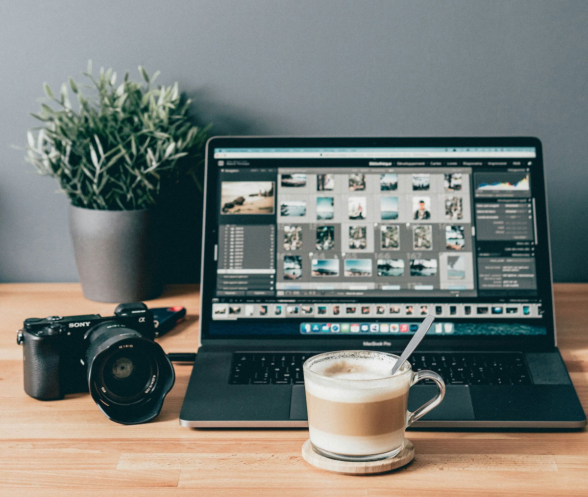 laptop with lightroom surrounded by camera coffee and a plant