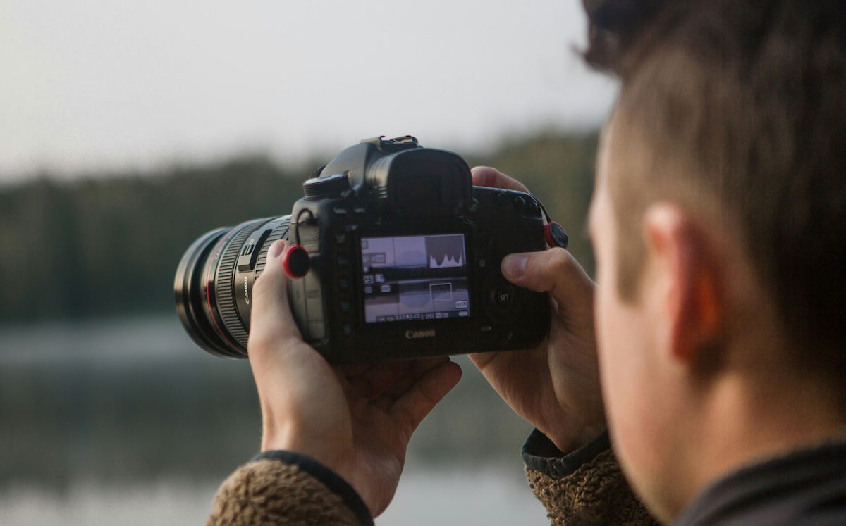 man holding camera up to his eye, camera shows histogram 