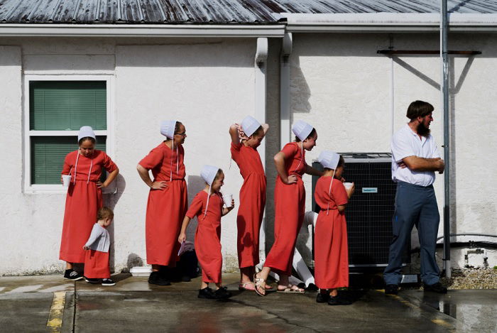 Group of Amish women and one Amish man by a wall