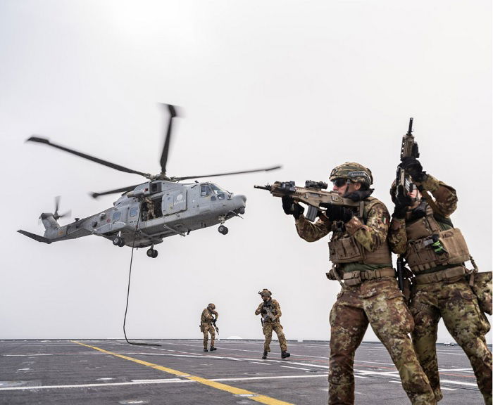 Soldiers on a helipad with helicopter taking off