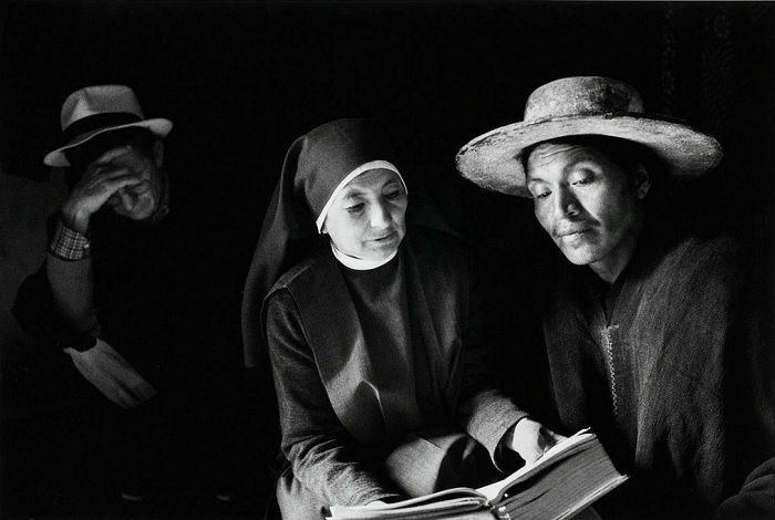 Two women reading bible with man behind