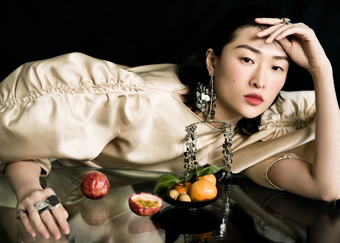 Woman in white dress leaning on reflective table