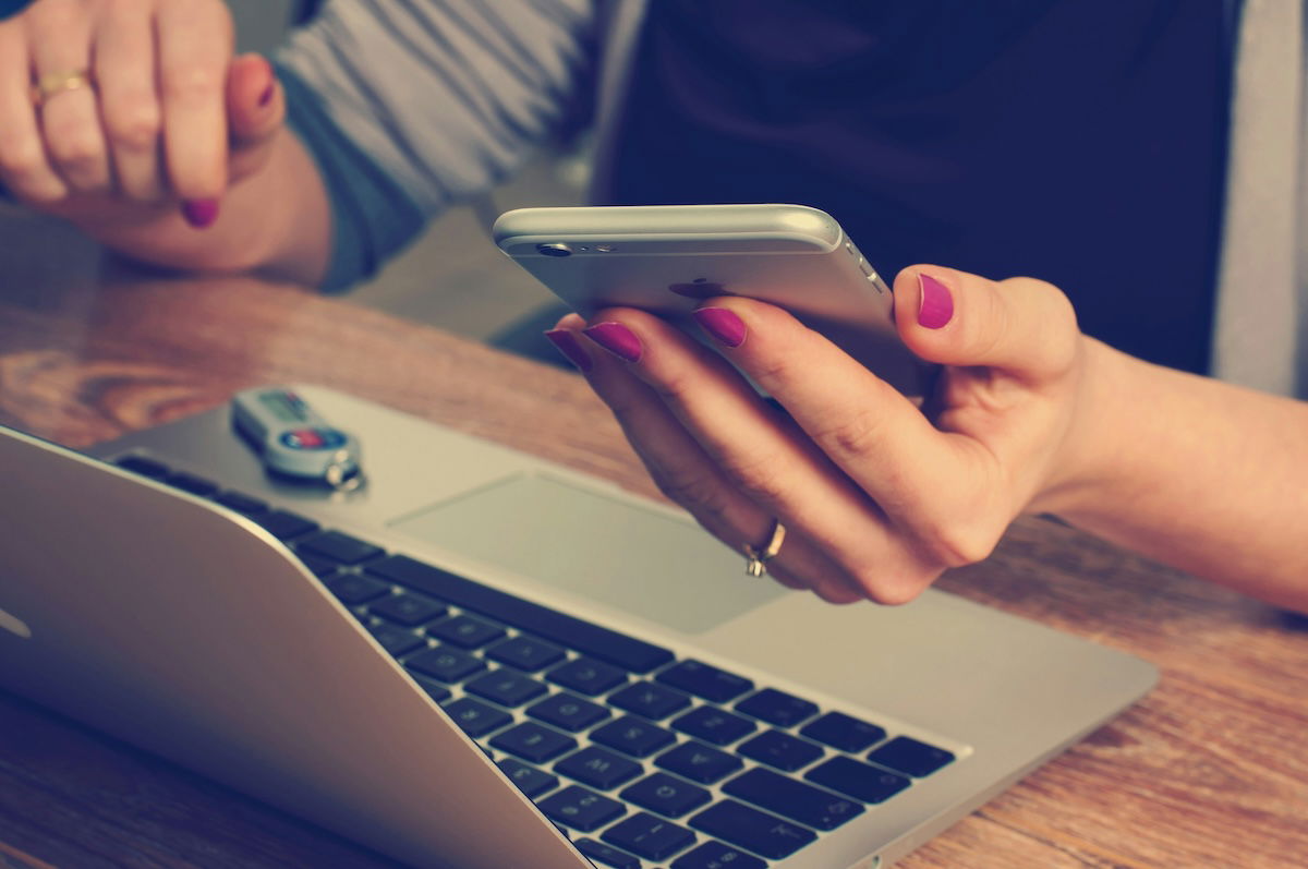 photo of person holding smartphone near computer