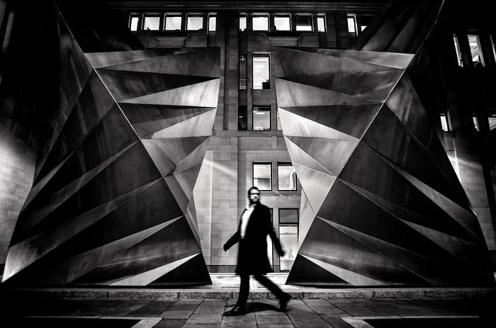 Blurred man walking in street with brutalist architecture