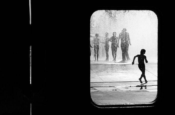 Children playing in a fountain seen through a doorway