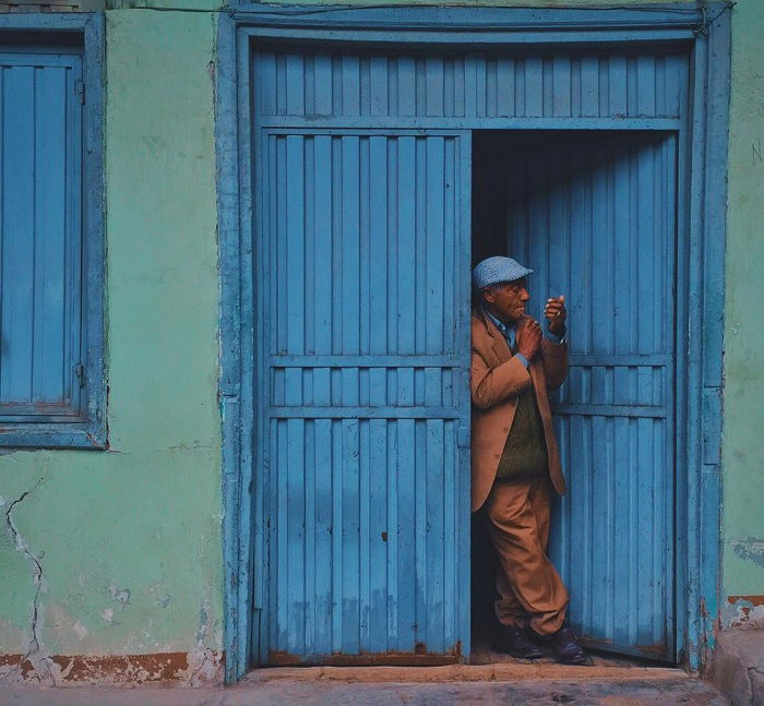 Old man coming out of a blue door