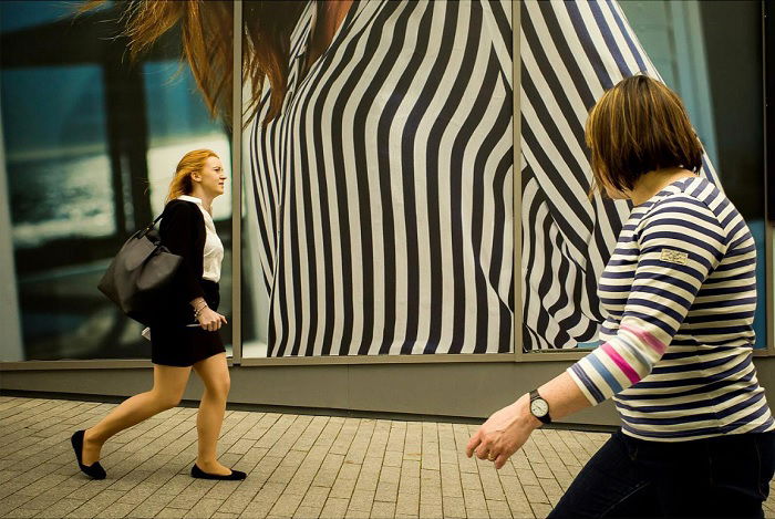 Woman in stripped top walking past big advert of woman in stripped top