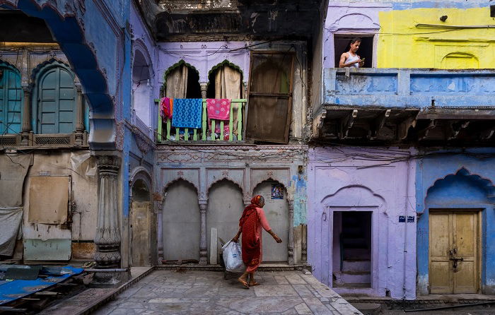 Woman carrying basket near purple houses