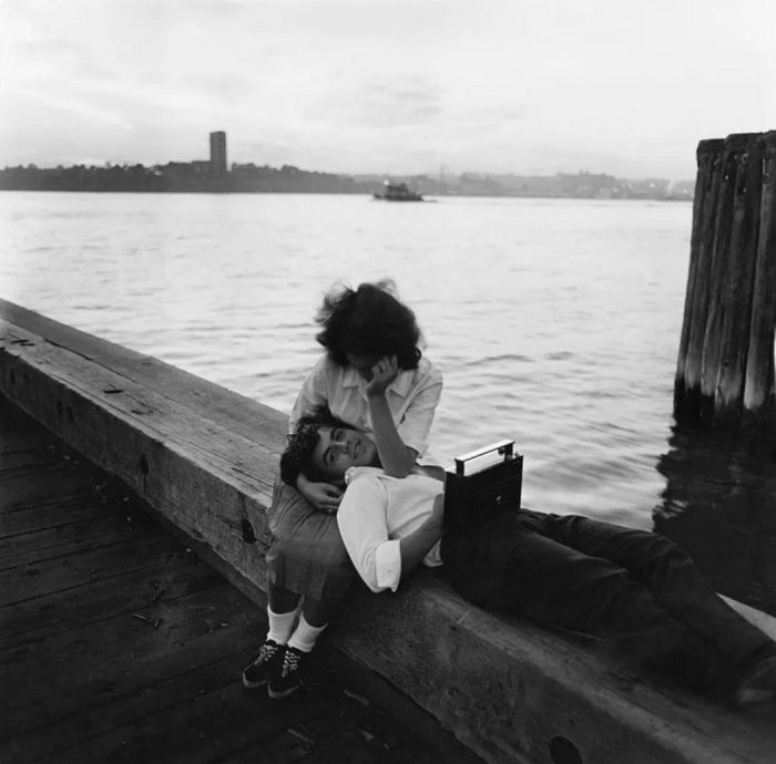 Man lying with head on womans lap on pier