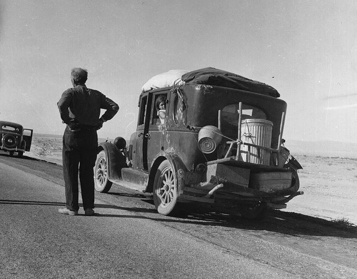 Man standing next to an old car on the road