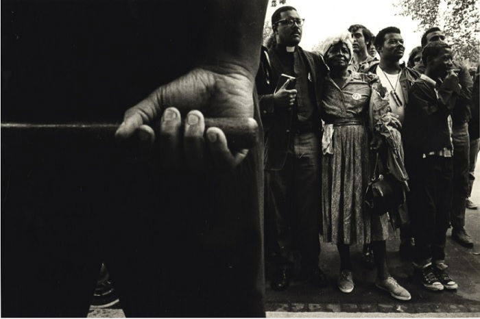 Hand with baton in front of crowd of black people