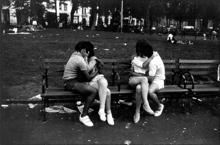 Two couples kiss in a bench