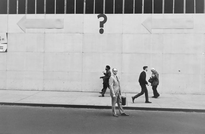 Man standing under question mark sign