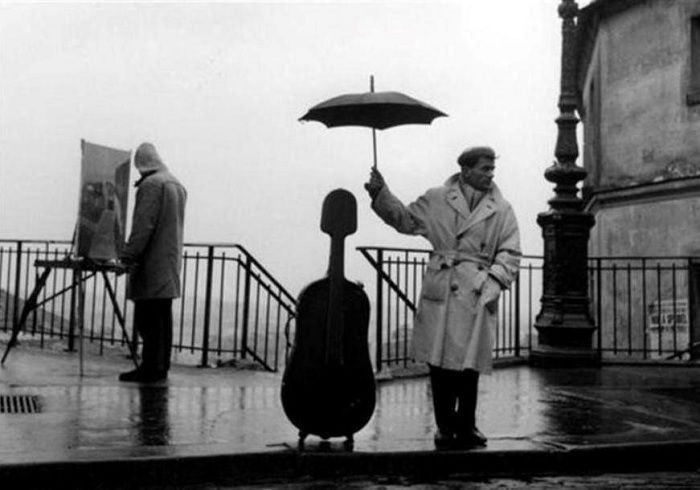 Man protecting cello case with umbrella