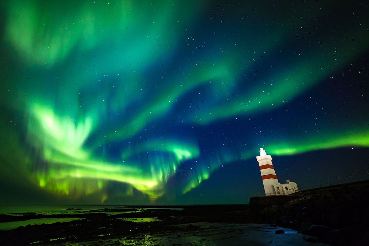 photo of the northern lights with lighthouse in the foreground