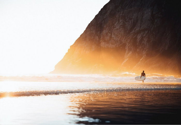 One surfer heading out into the waves at dawn