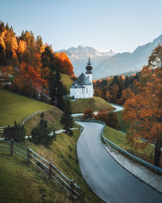 Valley road with white church and autumnal trees