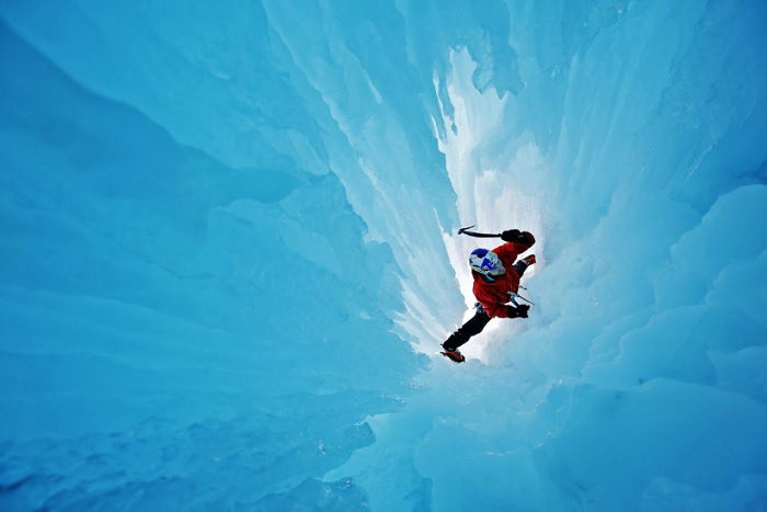 Climber climbing through ice tunnel