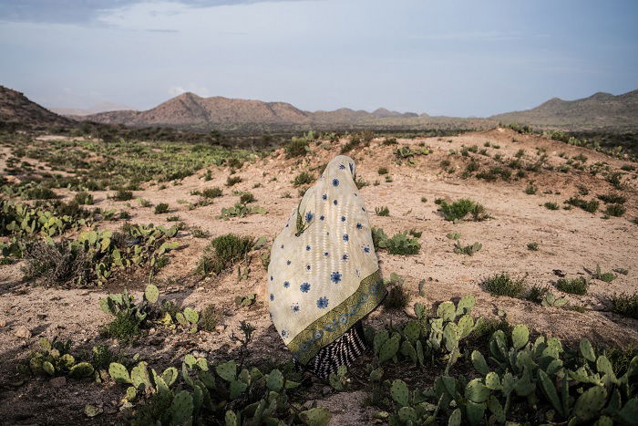 Woman in shawl that matches the desert surroundings