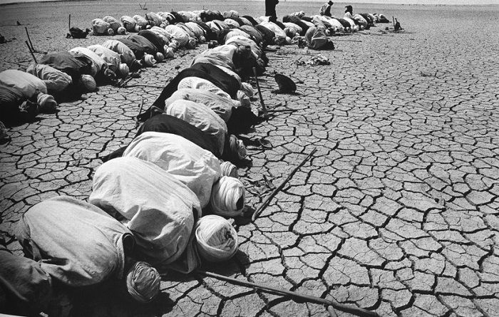 Men in Mali praying on parched ground