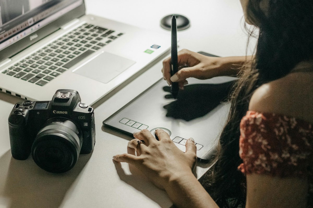 person working at a laptop using a graphics tablet with a camera on the table