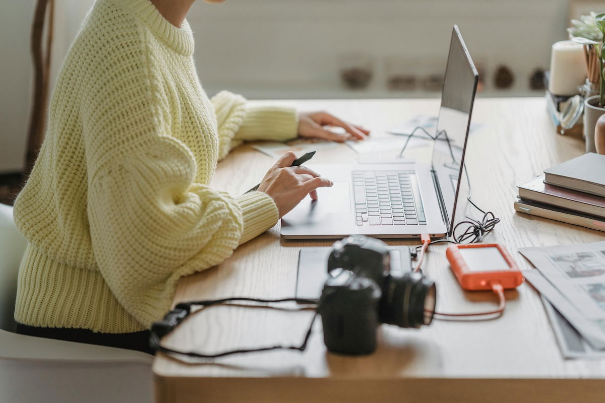 person working at a laptop with camera equipment on desk