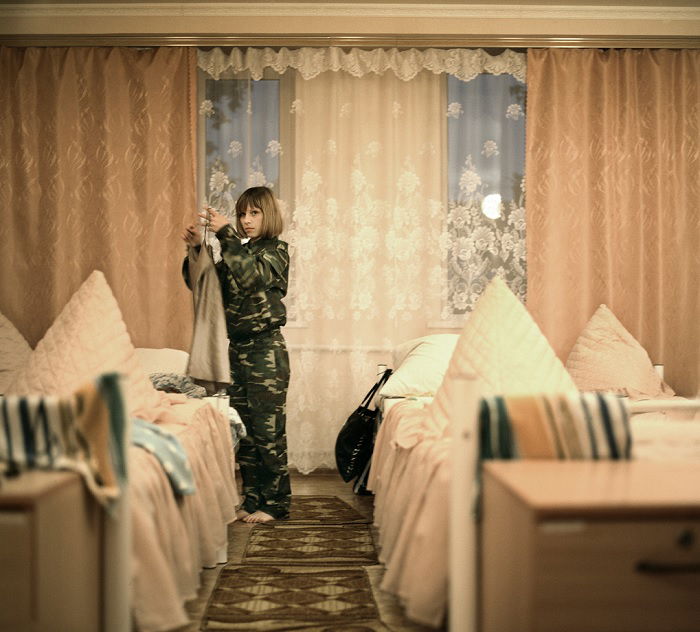 Young women in military garb dressing a bed