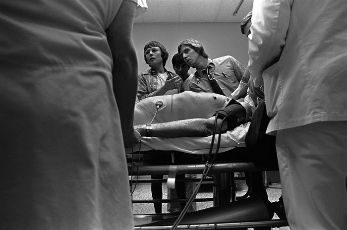 Doctors and nurses around sick person on hospital bed