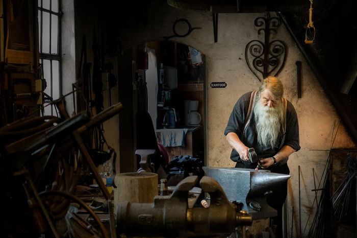 Bearded blacksmith working in workshop