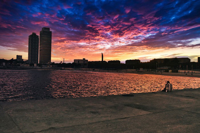 Man sitting on pier in barcelona beach edited with Luminar Neo